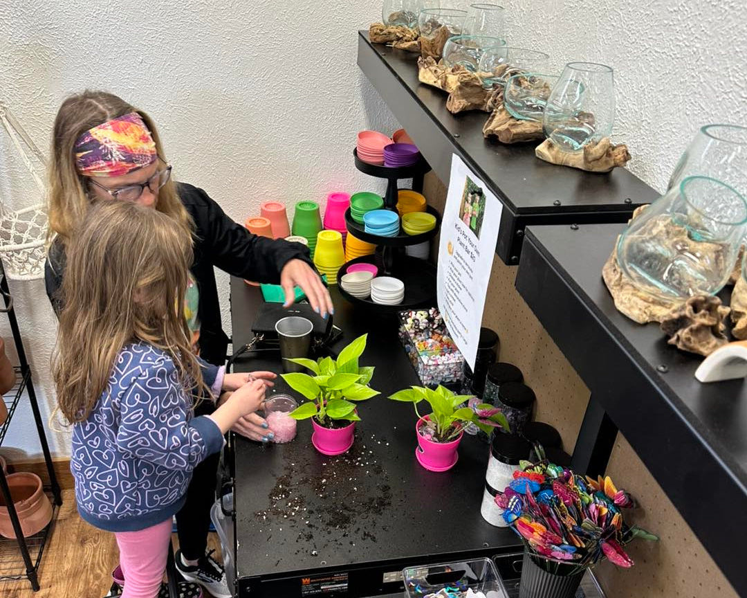 Two children interacting with small plants on a table in a store setting.
