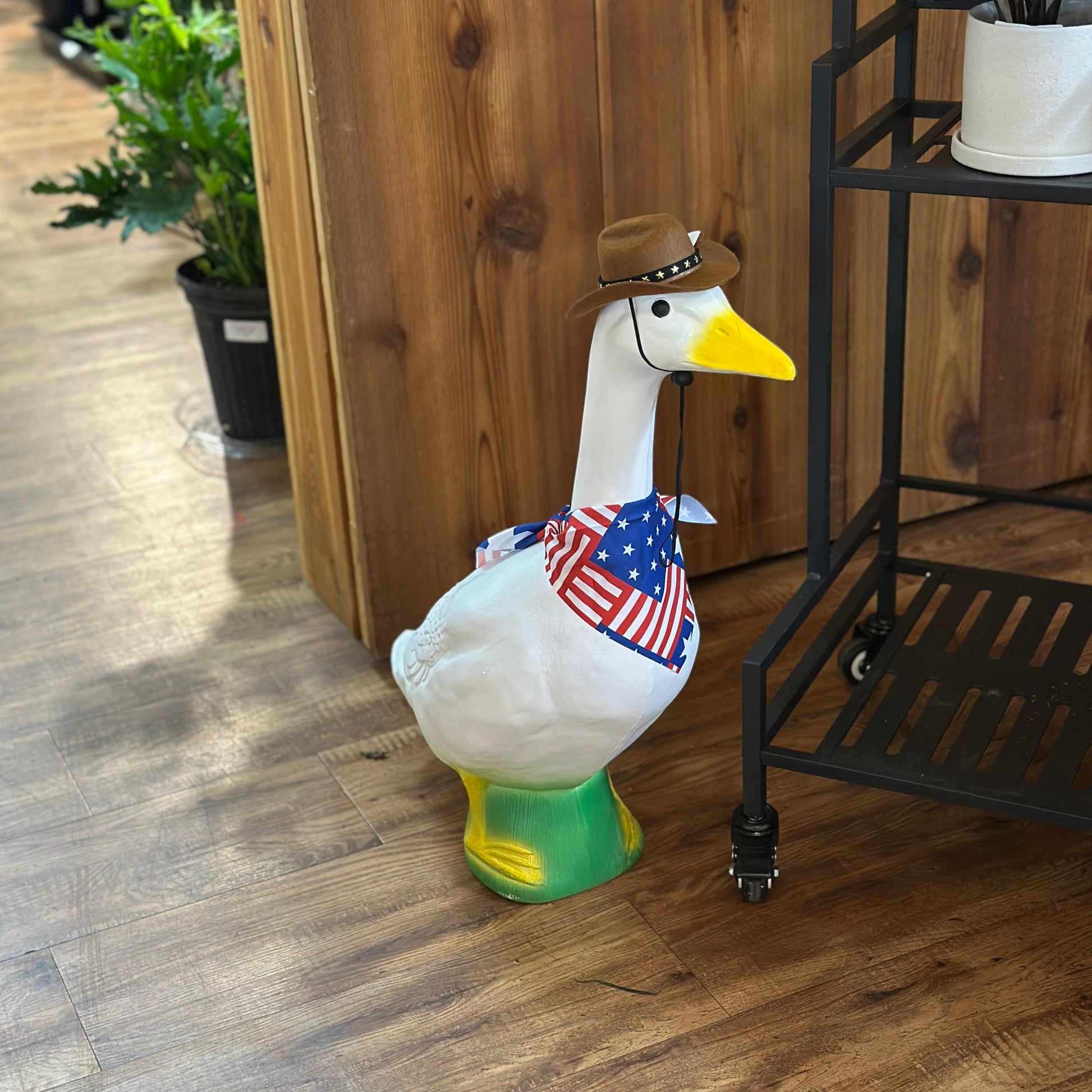 Decorative goose figurine with a hat and American flag on a wooden floor.