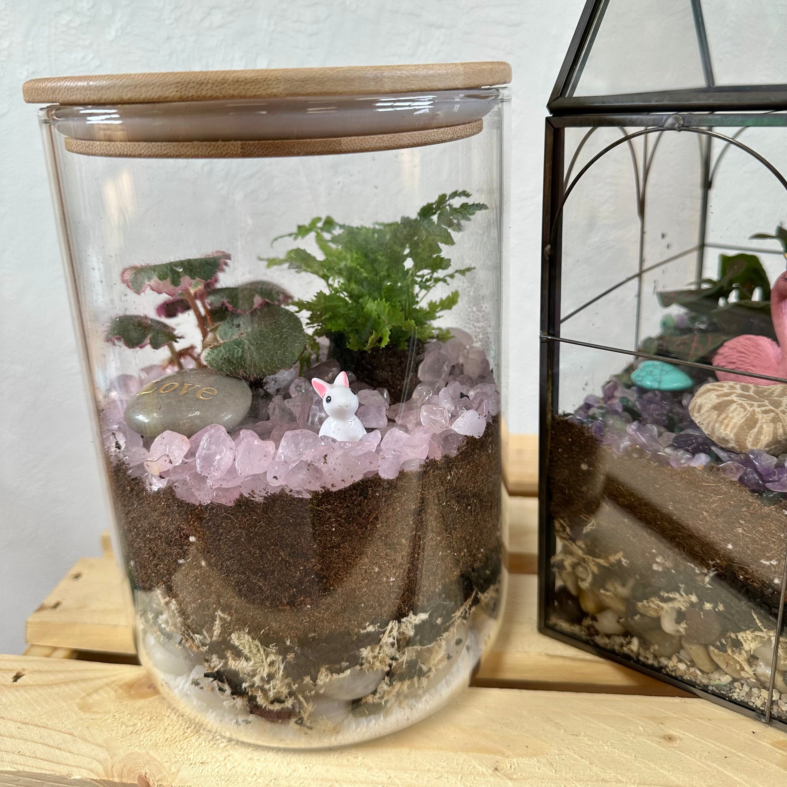 Glass terrarium with plants and decorative elements on a wooden surface