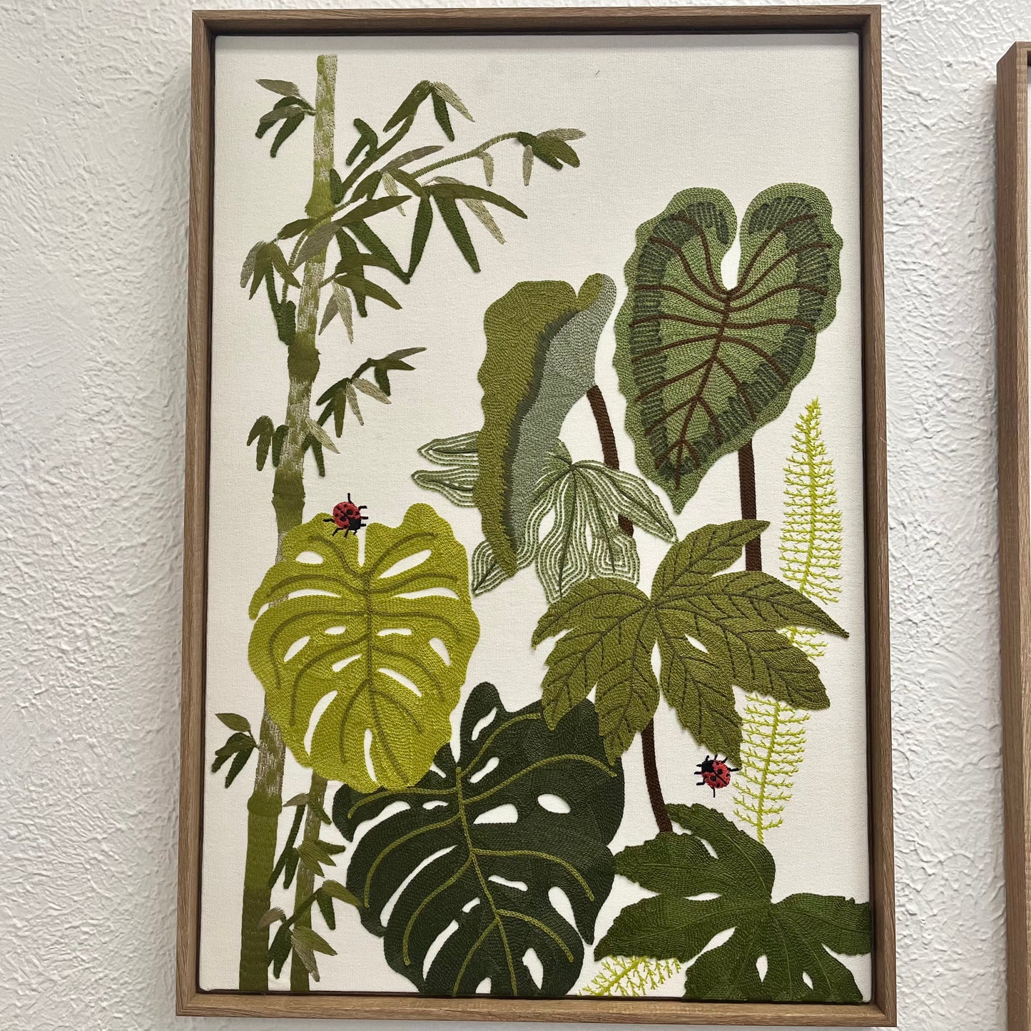 Framed artwork with green leaf patterns on a textured wall