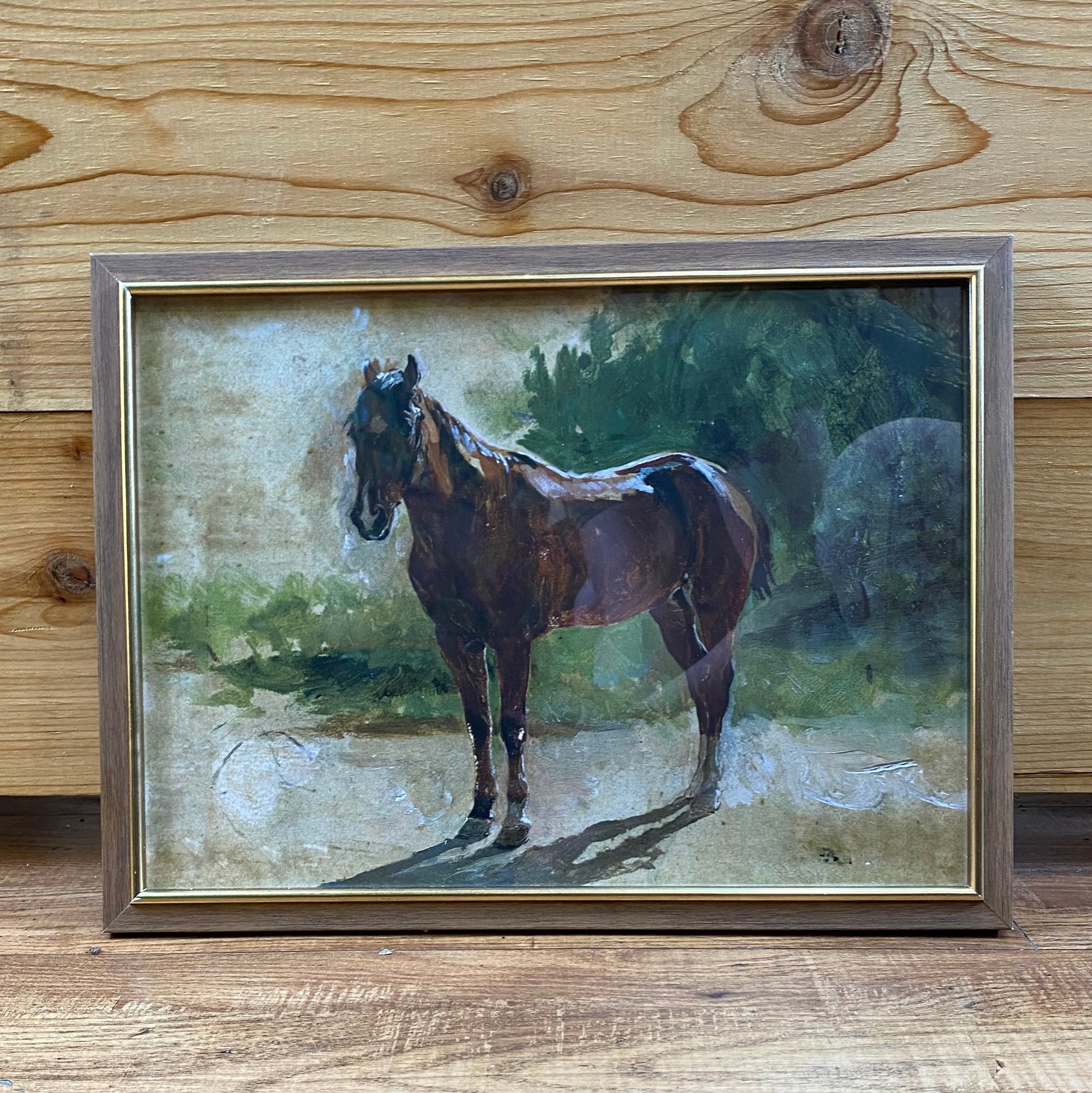 Framed painting of a horse on a wooden surface
