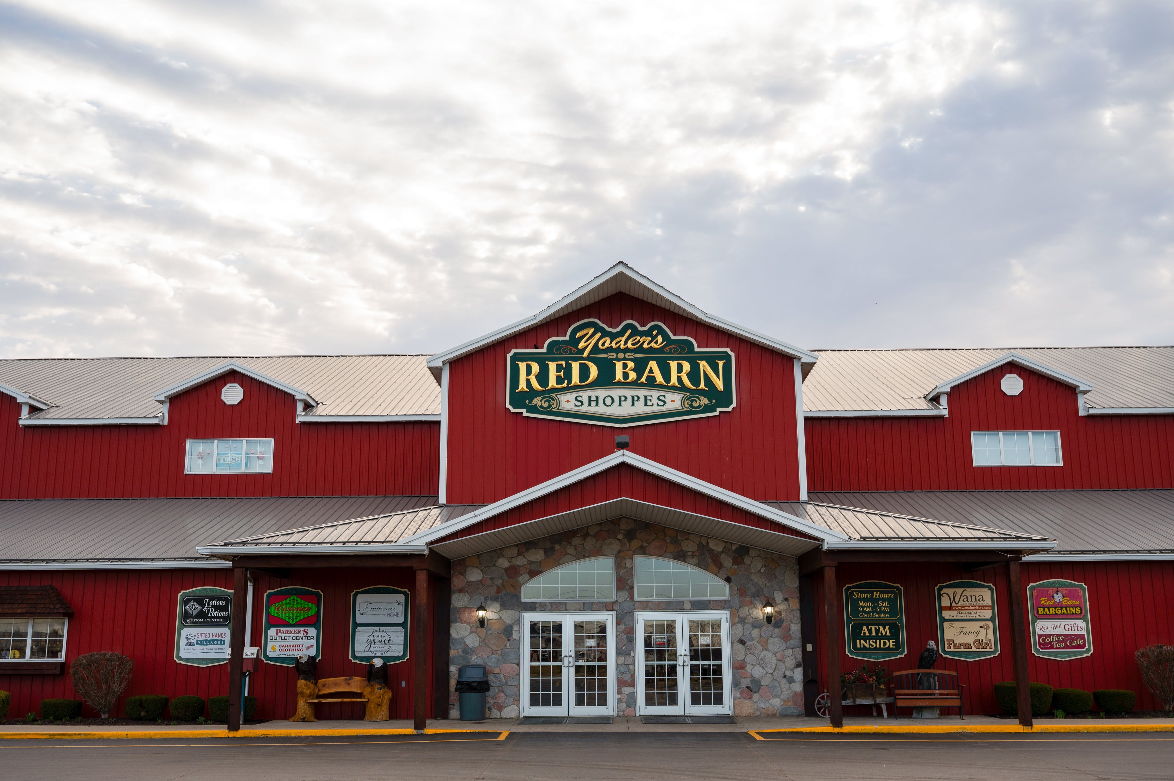 Red barn-style building with 'Yoder's Red Barn Shoppes' sign under a cloudy sky